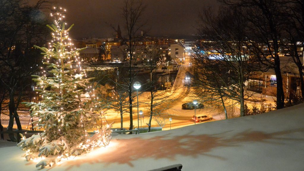 Oplyst juletræ i sne over en dansk by en decemberaften