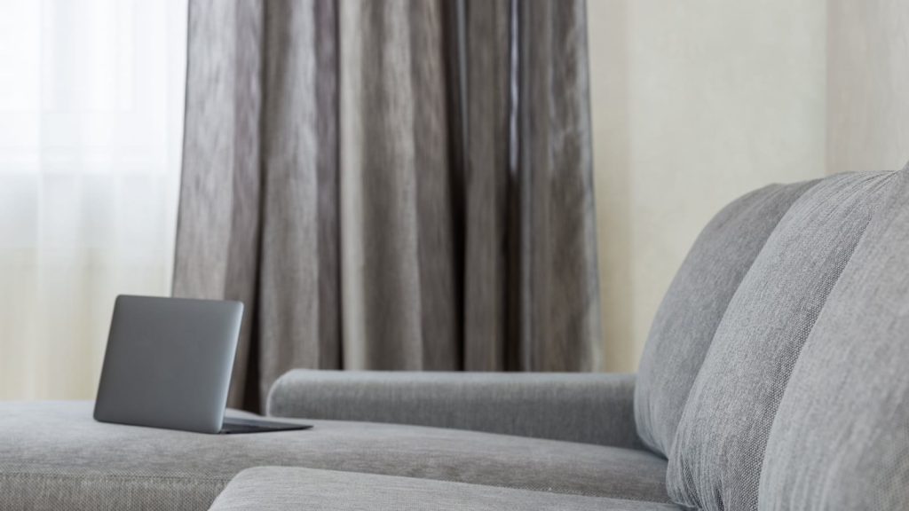 Bærbar computer på en grå sofa i en stue