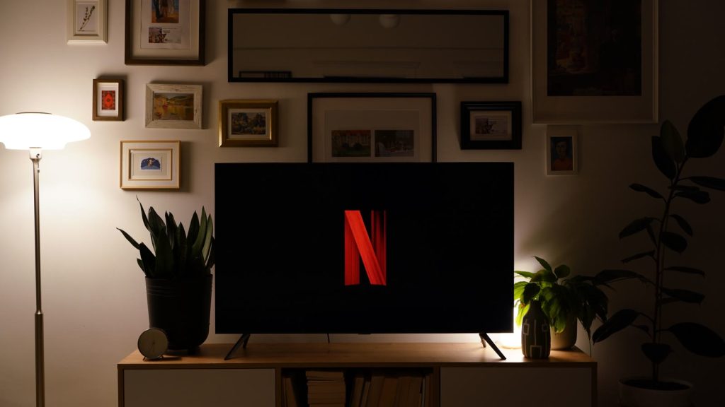 Fjernsyn med Netflix-logo i en mørk stue med plakater på væggen